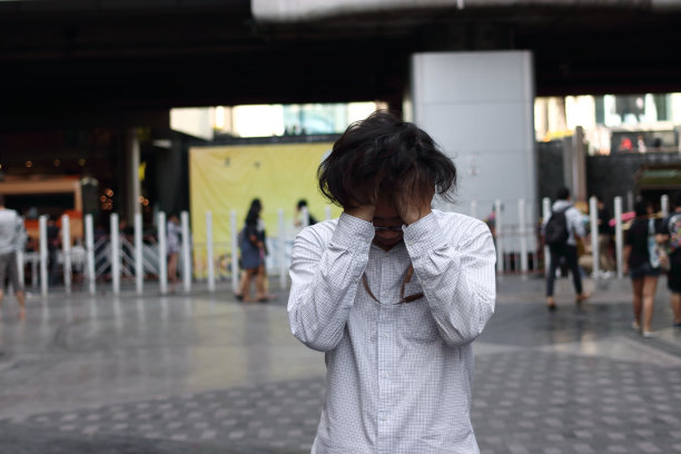 焦虑紧张的亚洲男子覆盖额头与手户外。图片下载