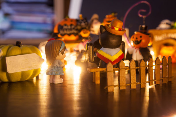 在南瓜门等待拍照的女孩们带着空白的招牌欢迎来到万圣节派对屋。节日庆典，节日，乐趣，万圣节玩具和娃娃装饰主题概念。图片下载