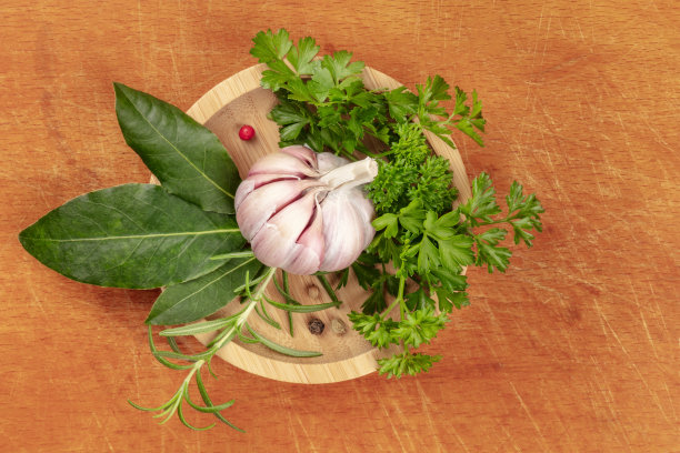 头顶上的照片，大蒜，芳香的厨房香草和香料，从上方拍摄的木碗，在一个乡村砧板的背景，有一个地方的文字图片下载