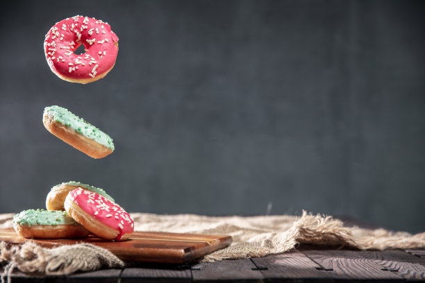 用粉色和绿色的糖霜点缀的甜甜圈，覆盖在带有文本空间的质朴桌子上。照片的水平方向。图片下载