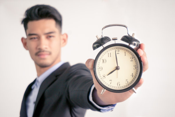 老板拿着一个闹钟提醒自己在白色背景下准时开始工作，不要迟到图片下载