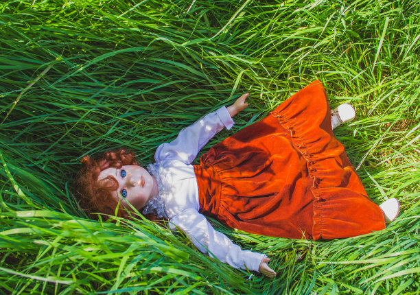 和平和安静。红头发的娃娃躺在绿色的草地上。和平或育儿理念。图片下载