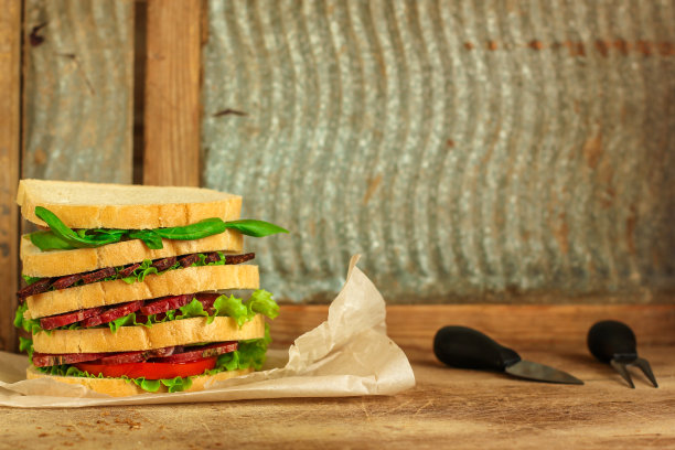 三明治-面包，肉，罗勒，新鲜的莴苣叶在木制的背景。前视图。本空间图片下载
