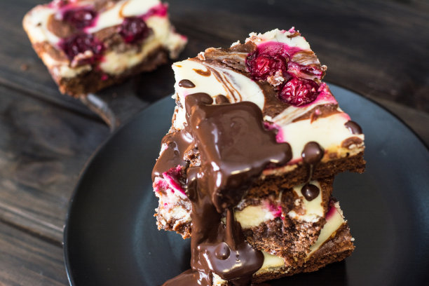 巧克力芝士蛋糕，分层的布朗尼和黑樱桃。红巧克力蛋糕。几块巧克力蛋糕。冬天的甜点。传统的美国菜。食物的静物。黑色食物的照片。图片下载