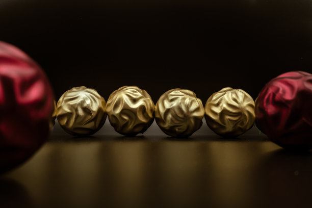 在黑色的背景上，金色和红色的小球为圣诞树。图片下载