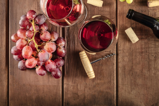 在酒窖里品酒。这是一张红色和玫瑰葡萄酒杯与酒瓶，葡萄，和一个古老的瓶塞和软木塞的照片，从上面拍摄在一个黑色的乡村木制背景和一个地方的文字图片下载