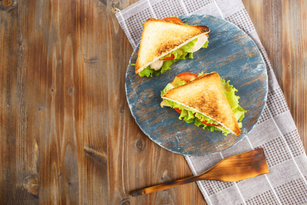 两个美味的三明治与鸡肉，西红柿，生菜，奶酪在木盘子上，在黑暗的背景图片下载