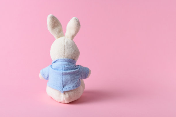 粉色背景上的白兔娃娃。最小的概念。图片下载
