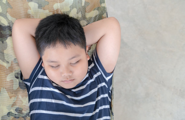 肥胖的胖男孩睡在公园的摇篮上图片下载