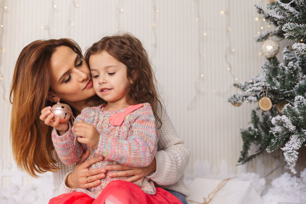 年轻的妈妈和她的女儿在平安夜玩得开心图片下载