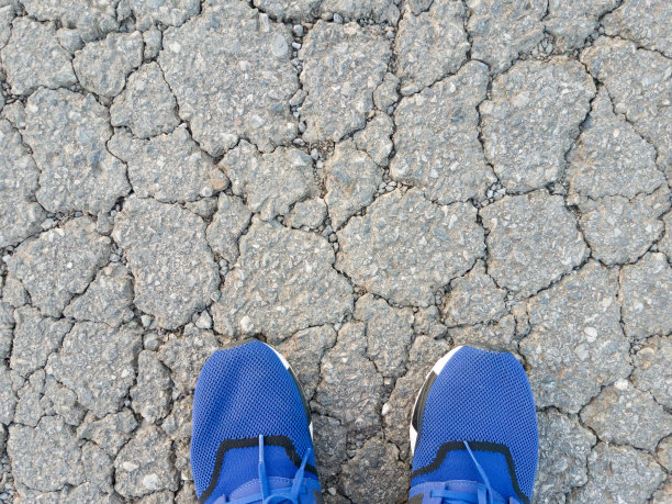 蓝色运动鞋在柏油路上有裂缝图片下载