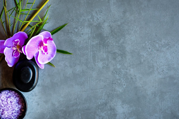 泰国Spa。顶视图热石设置按摩治疗和放松与紫色兰花黑板与复制空间。绿叶与黑色的石头堆作spa。图片下载