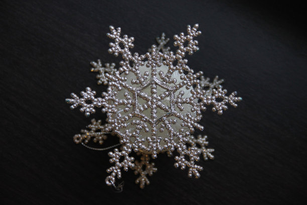 美丽的圣诞闪光雪花在黑暗的木制表面特写图片下载