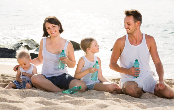 一对夫妇带着两个孩子在沙滩上喝着淡水图片下载