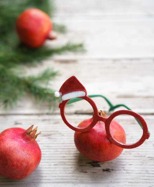 鲜艳的红色圣诞石榴眼镜与节日装饰框架和冷杉树枝在乡村灰色木制背景。圣诞新年展示健康眼睛的概念。本空间图片下载