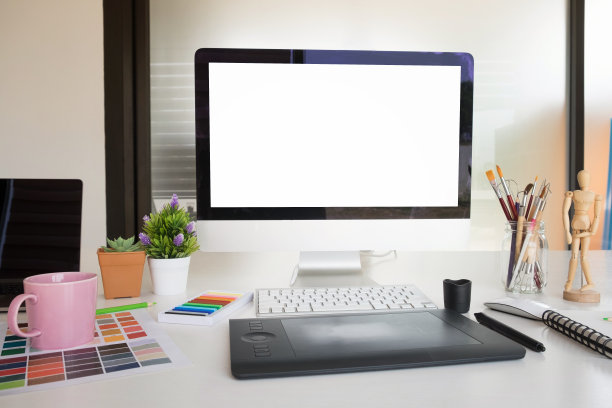模型艺术家的工作场所与电脑电脑和一杯咖啡在书桌上与空屏幕电脑显示。图片下载