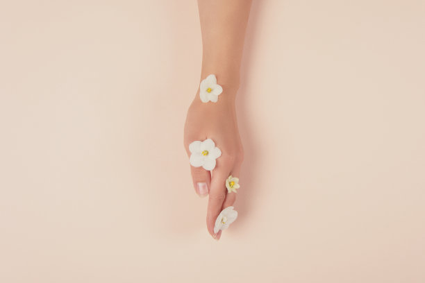 粉红色背景上有白花的手。皮肤护理的概念。前视图。副本的空间。健美的图片下载