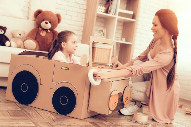 妈妈和女孩在家里制造汽车纸板。图片下载