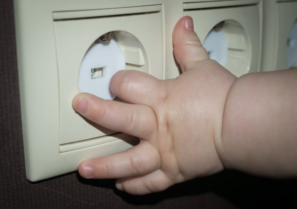 婴儿的手伸向覆盖着安全插头的电源插座。婴儿和儿童安全概念图片下载