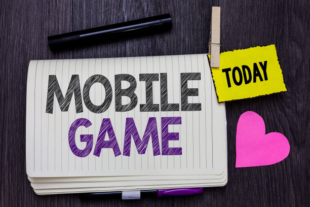 文本标志显示手机游戏。概念照片，他们是娱乐节目制作在智能设备上工作打开笔记本，晾衣夹夹着提醒标记心木制背景。图片下载