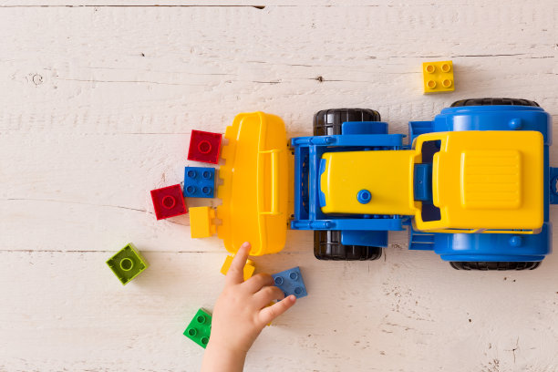 小男孩的手玩彩色玩具拖拉机的特写。在托儿所或学前班玩汽车的孩子。图片下载