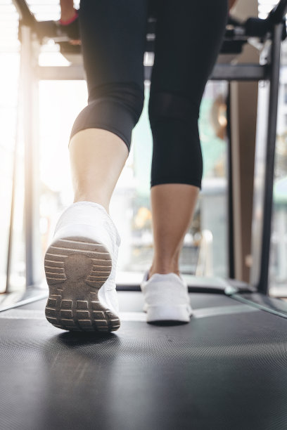 健身女性的腿在跑步机上或跑步机上，在健身房里与阳光图片下载