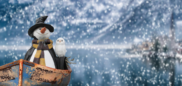 圣诞快乐雪人在一个寒冷的冬天，雪山景观湖面上漂浮的小船图片下载
