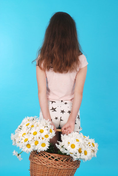 后景少女手捧一束洋甘菊望着墙。图片下载