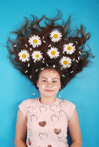 一个头发上插着雏菊的年轻女孩的画像躺在地板上图片下载