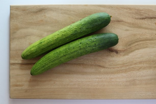 两根黄瓜放在木砧板上图片下载