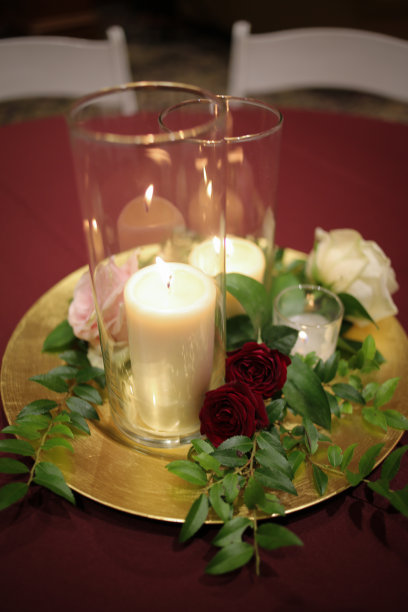 婚礼中心蜡烛周围的绿色植物在一个金充电器盘子图片下载