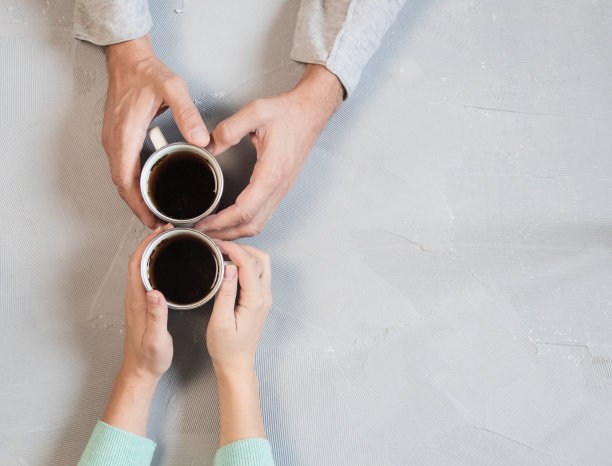 相爱的情侣手牵着手，在白色大理石桌上喝咖啡。从上面拍摄的照片，带有拷贝空间的俯视图图片下载