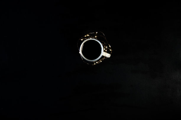 黑色的桌子上放着一杯咖啡，还有圣诞彩灯。从上面拍摄的照片，带有拷贝空间的俯视图。图片下载