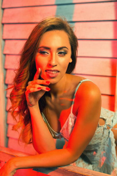 穿着蕾丝衬衫的漂亮年轻女子，倚在海边房子的栏杆上图片下载