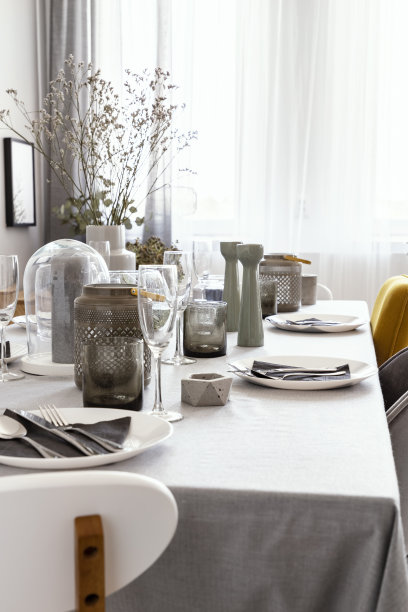 在明亮的餐厅内设有窗户的餐桌上放有植物的盘子和餐具。真实的照片图片下载