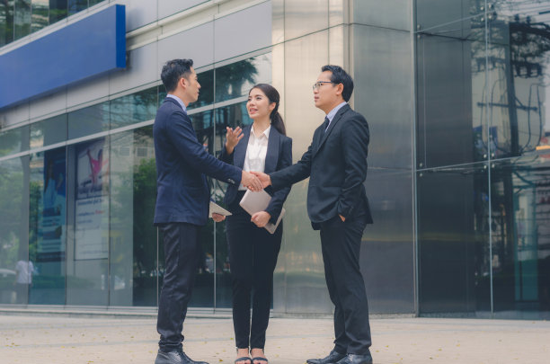 两个有吸引力的商业男人和一个商业女人在城市的现代建筑办公室的户外一起谈论商业讨论。企业团队合作的领导理念。图片下载