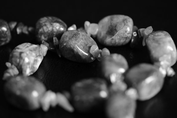 一条项链的碎片从一个天然的石头在一个黑暗的背景近距离。黑色和白色图片下载