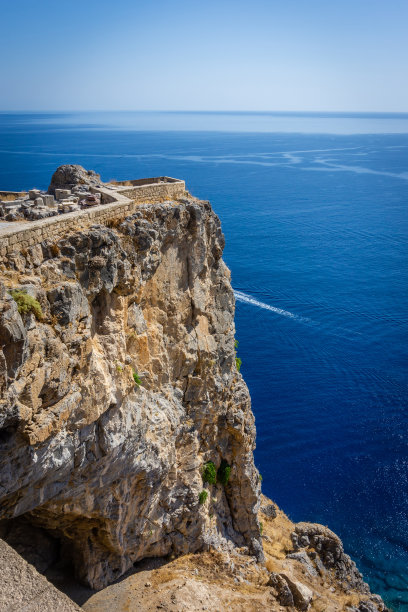 在地中海和林多斯镇上方的古代卫城的一部分垂直照片。卫城在罗德岛上。在岩石后面可以看到蓝色的大海和晴朗的天空。图片下载