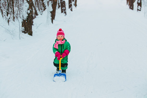 可爱的小女孩在大自然的冬天挖雪图片下载