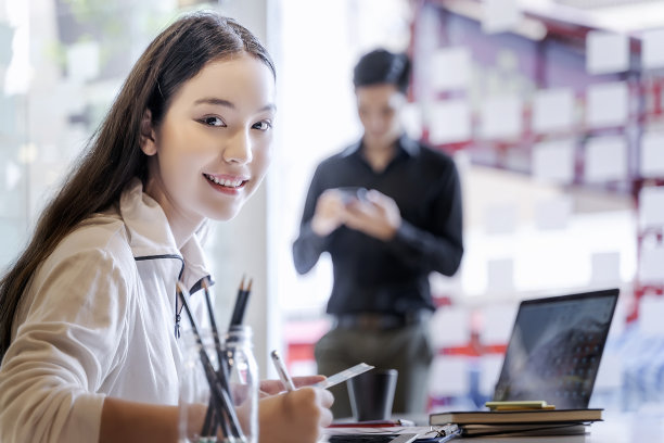 年轻的女商人坐在她的办公室里，面带微笑地看着镜头图片下载
