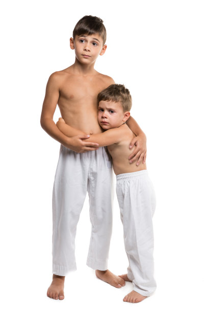 两个男孩穿着运动服为空手道，两个兄弟，哥哥保护弟弟，概念，在一个白色的背景，孤立图片下载