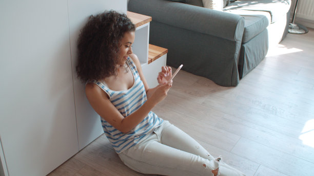 迷人的年轻女子在家里用手机打字。图片下载