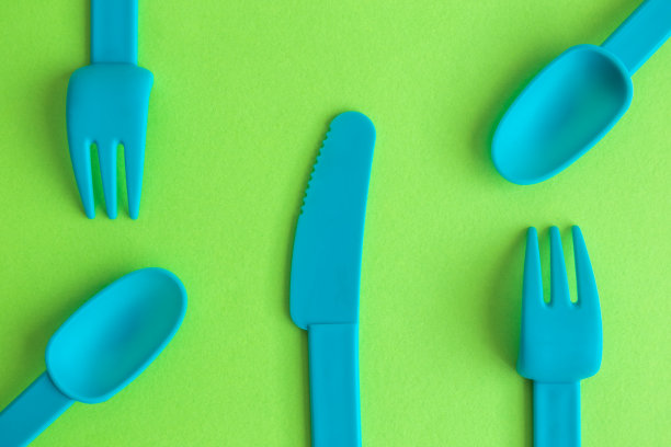 塑料餐具抽象孤立在绿色。图片下载