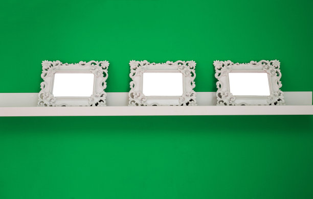三个白色的空相框在绿色的墙壁和木制的架子上，孤立的，文字或照片的空间图片下载