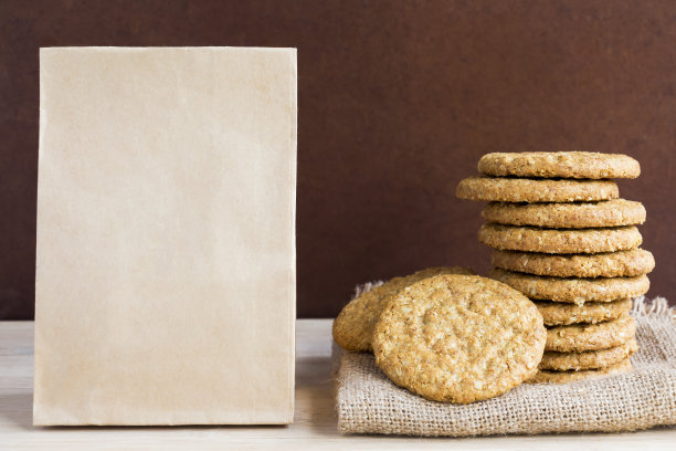 木桌背景上的麻袋和纸袋上堆放着自制的燕麦脆饼。概念食品，假日享用的健康零食。与复制空间的文本。图片下载
