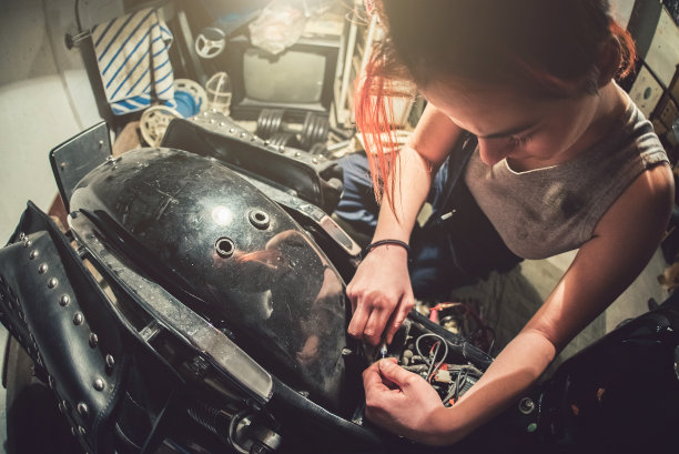 一个女机修工在摩托车车间修理摩托车。图片下载