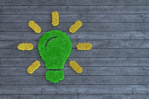 彩色灯泡符号由人造草在深色木材上制成图片下载