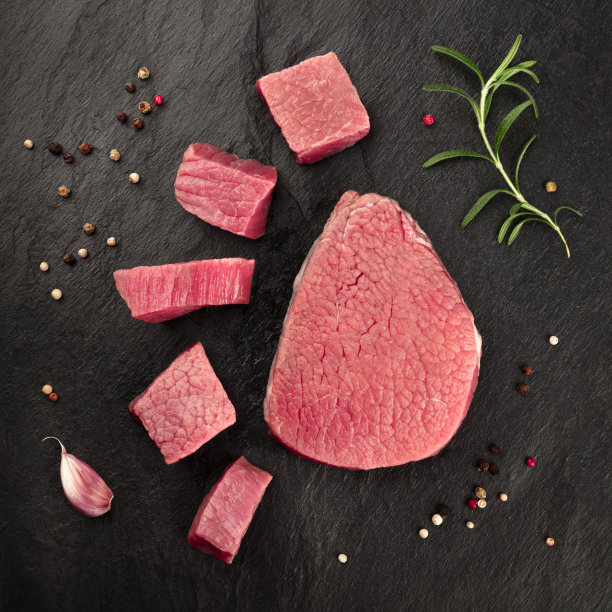 在黑色的背景下，用迷迭香、大蒜和胡椒从上方拍摄的生牛肉片图片下载