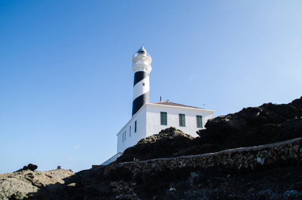 这是一幅被岩石、大海和海滩包围的曼诺卡灯塔的风景照片。图片下载