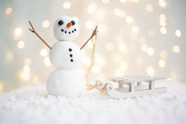 新年和圣诞节的礼物卡与一个雪人与雪橇在一个发光的花环的背景的图片图片下载